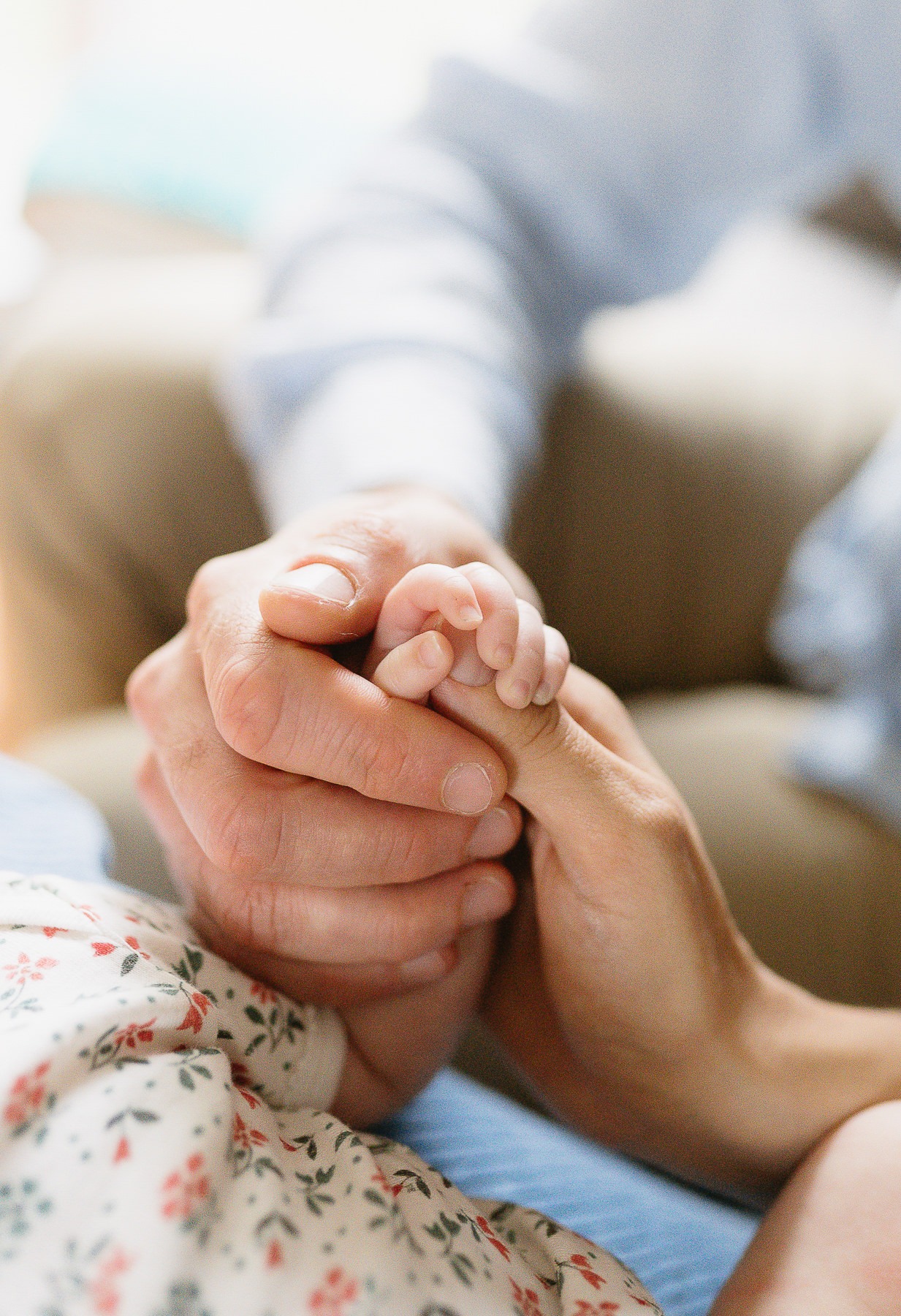 séance photo naissance à domicile : les mains des parents entourant avec douceur la petite main de leur nouveau-né, photographe à Bain-de-Bretagne.